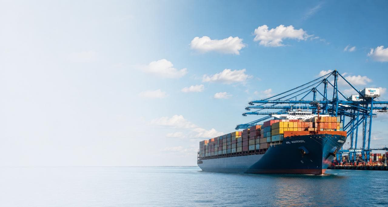 Container ships loading cargo under gantry cranes at a port at sunset